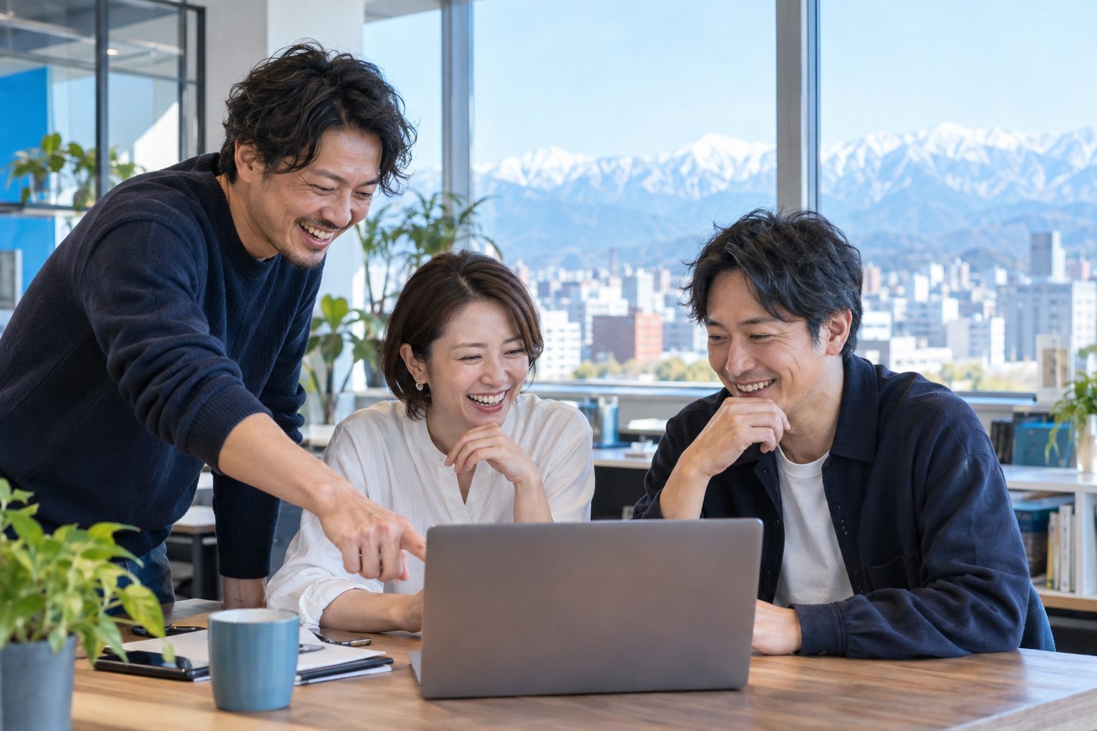 笑顔でノートパソコンを囲み、AIの使い方を試す職場の仲間